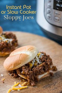 two sloppy joes on a cutting board next to an instant pot or slow cooker