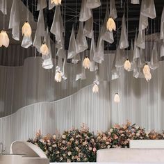 a room filled with lots of white flowers and lights hanging from it's ceiling