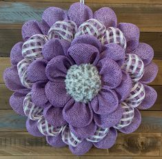 a purple and white mesh flower hanging on a wooden wall next to wood planks