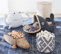 three sea themed baskets sitting on top of a blue rug next to two fish figurines