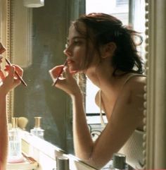 a woman is brushing her teeth in front of a mirror while looking at herself in the mirror