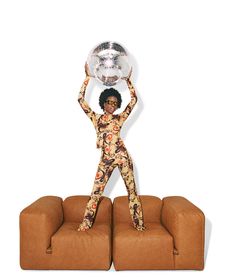 a woman standing on top of two couches holding a disco ball above her head