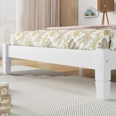 a white bed frame with flowers and leaves on it