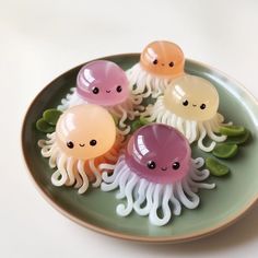 four jellyfish on a plate with green leaves and one is pink, yellow, and white