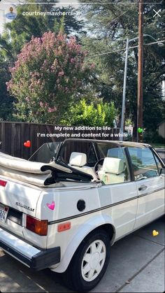 a white car is parked on the side of the road with a surfboard strapped to it's roof