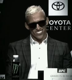 a man wearing sunglasses sitting in front of a bottle of monster energy on a table