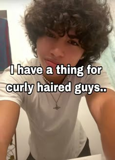 a man with curly hair is looking at the camera and has his hand on his head