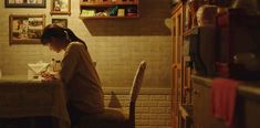 a woman sitting at a table in front of a book shelf with books on it