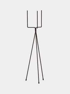 a black metal tripod stand with two legs and one leg on the ground, in front of a white background