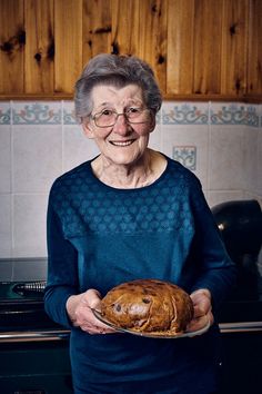 an older woman holding a loaf of bread