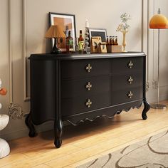 a black dresser sitting in a living room next to a lamp