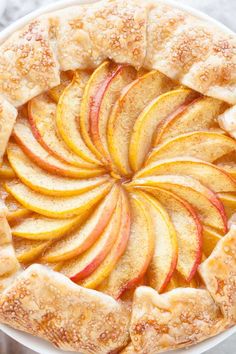 an apple pie with sliced apples on top in a white pie dish, ready to be eaten