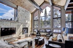 a living room filled with lots of furniture next to a fire place and large windows