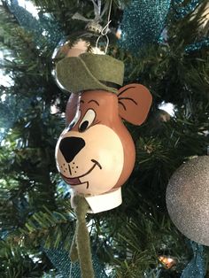 a close up of a christmas tree with ornaments hanging from it's sides and a bear ornament on the top