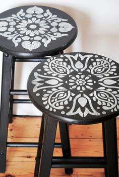 two black and white stools sitting next to each other on top of a wooden floor