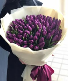 a woman holding a bouquet of purple tulips