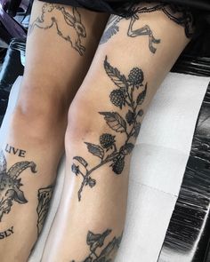 the legs of a woman with tattoos on them are covered in leaves and flowers,