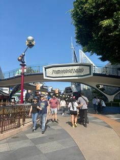 people are walking under the sign for tomorrowland at disneyland world in california, usa