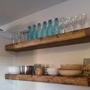 two wooden shelves filled with glass bottles and bowls