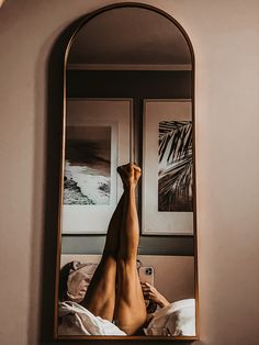 a woman laying on top of a bed in front of a mirror with her reflection