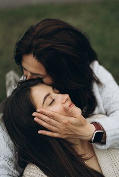 two women hugging each other in the grass with their hands on their face and one woman covering her eyes