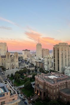 the city skyline is shown at sunset with tall buildings in the foreground and pink clouds in the sky