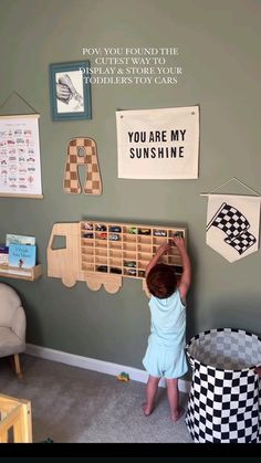 a young child playing with toys in a room that is painted green and has pictures on the wall