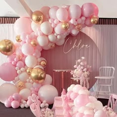 a table topped with lots of pink and gold balloons