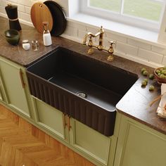 a black kitchen sink sitting on top of a counter next to green cabinets and wooden floors