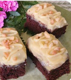 four pieces of cake sitting on top of a white plate with pink flowers in the background