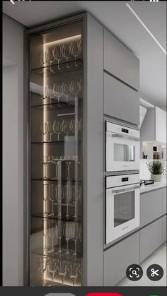 a kitchen with an oven, microwave and wine glasses on the cabinet door that is open