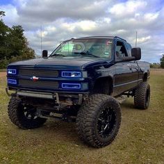 a black truck parked in the middle of a field