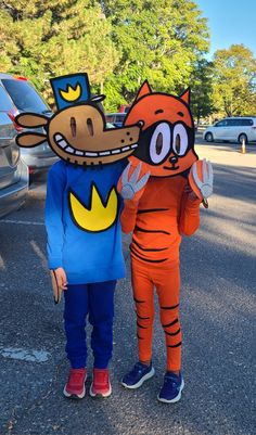 two people in costumes are standing next to each other on the street and one is wearing a costume that looks like a cat