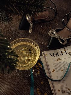 a glass of wine next to a magazine and some high heeled shoes on a table