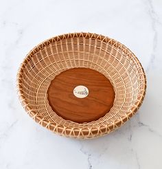 a wicker bowl with a wooden lid on a marble surface