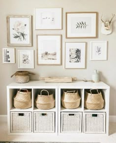 a white shelf with baskets and pictures on the wall next to a rug in front of it