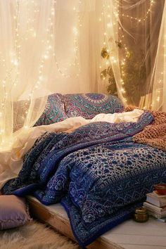 an unmade bed covered in blankets and lights