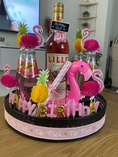 a pink flamingo themed birthday cake with pineapples and liquor bottles in the background