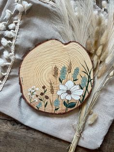 a piece of wood with flowers on it and some grass in front of the wooden slice