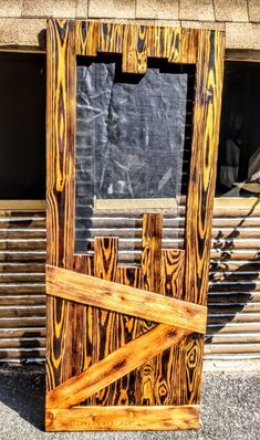 a wooden frame sitting on the side of a building next to a window with an open door