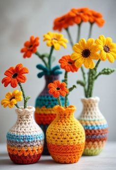 three crocheted vases with colorful flowers in them