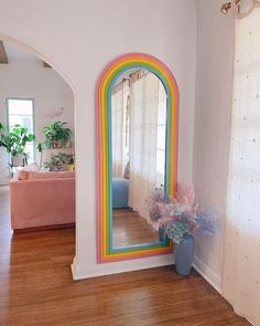 a room with a mirror, couch and potted plant on the floor in front of it