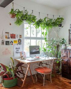 a room with a desk, chair and plants in the window sill next to it