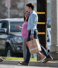 a man and woman walking down the street with shopping bags on their backs, one holding a cell phone