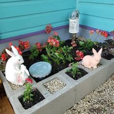 the garden is decorated with flowers, plants and bunnies in concrete block planters