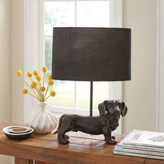 a dog figurine sitting on top of a wooden table next to a lamp