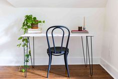 a black chair sitting next to a white table with a potted plant on it