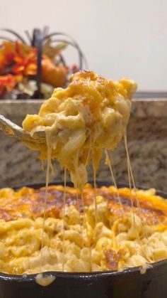 a spoon full of macaroni and cheese being lifted from a skillet