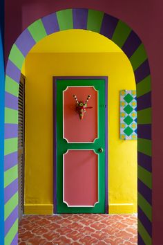 the door is painted bright pink, green and yellow with an unusual design on it