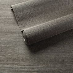 a roll of gray fabric sitting on top of a wooden floor next to a wall